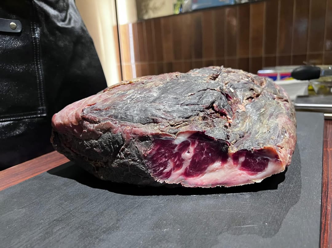 乾式熟成外殼特寫，深褐色硬殼與白霜下露出的紅色肉質切面
